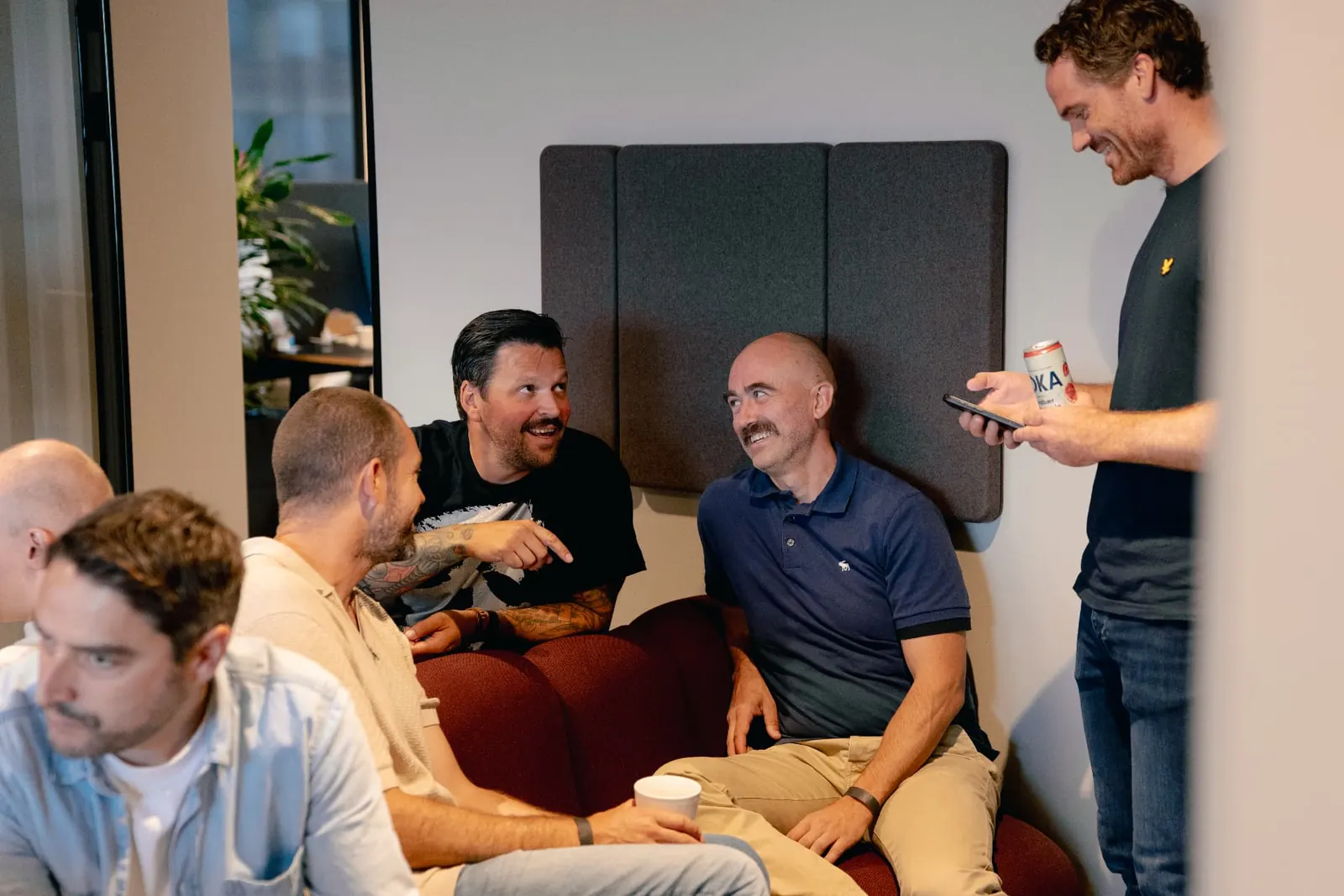 Colleagues laughing together on the sofas in the Oslo office
